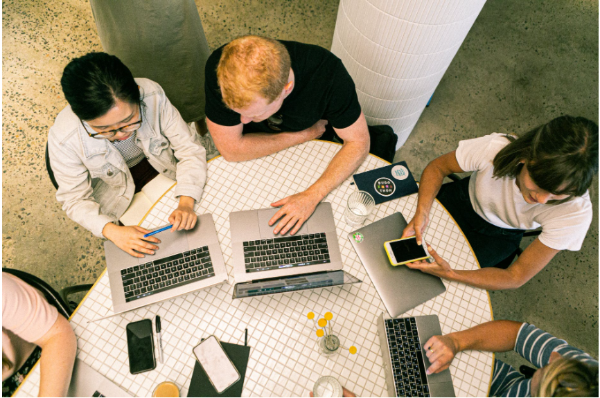 People sitting around a table with laptops opened on it